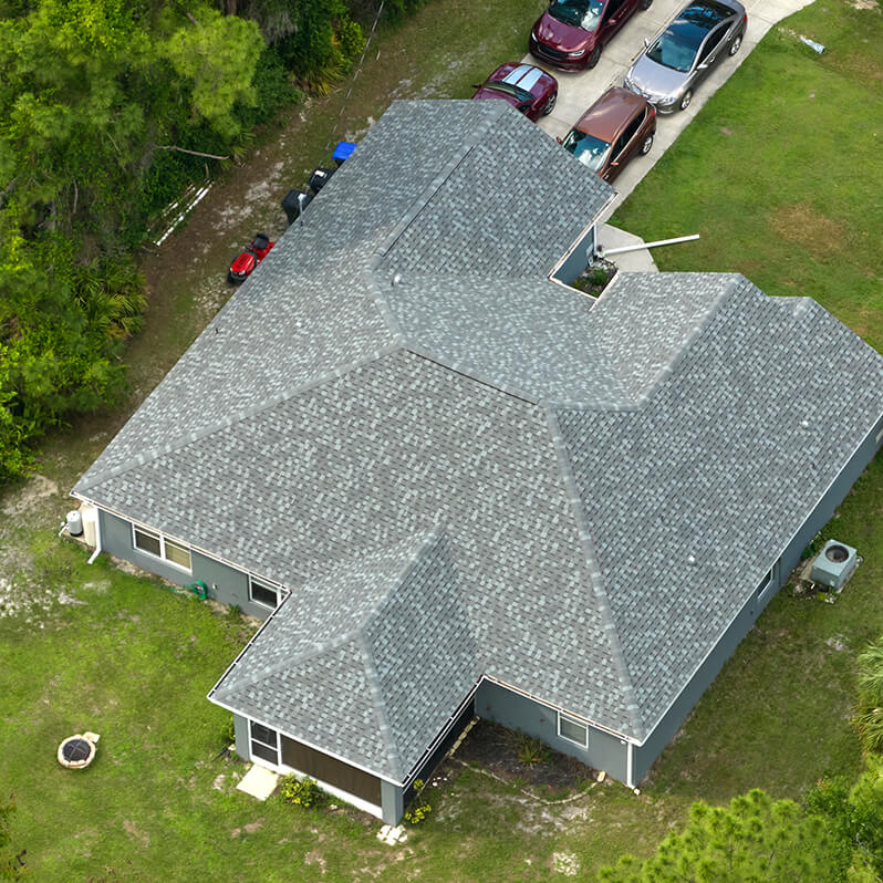 Aerial view of a home with a newly installed gray asphalt shingle roof, showcasing clean lines and multiple roof slopes for strong weather protection.